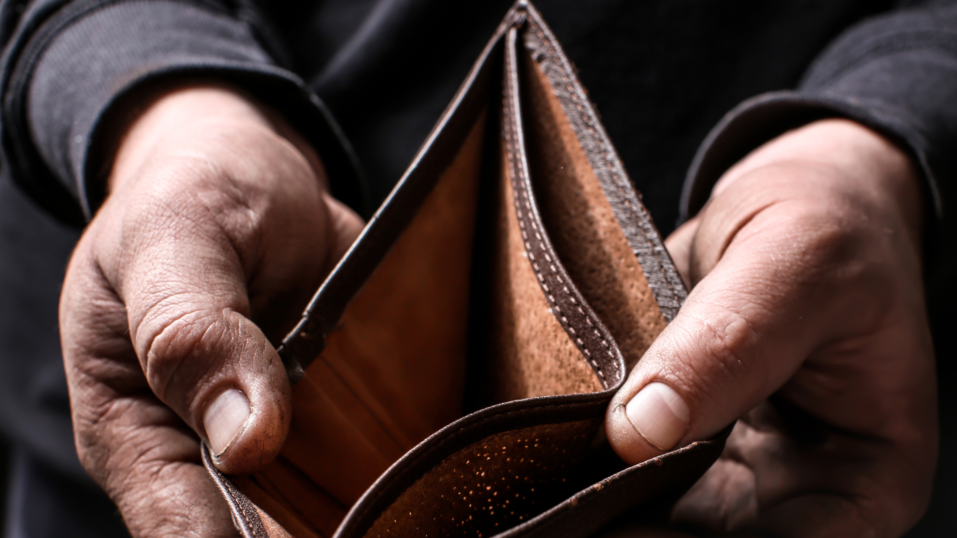 Mãos segurando carteira vazia, representando vulnerabilidade econômica e o benefício BPC do INSS